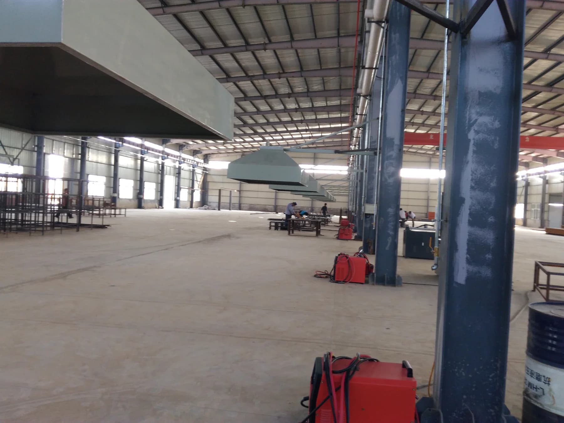Wide view inside a steel fabrication workshop with extraction hoods and workstations