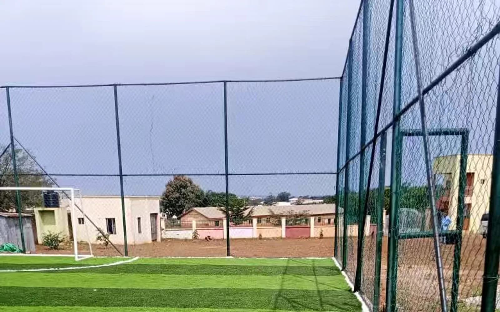 Artificial-turf football pitch and tall perimeter enclosure in Nigeria
