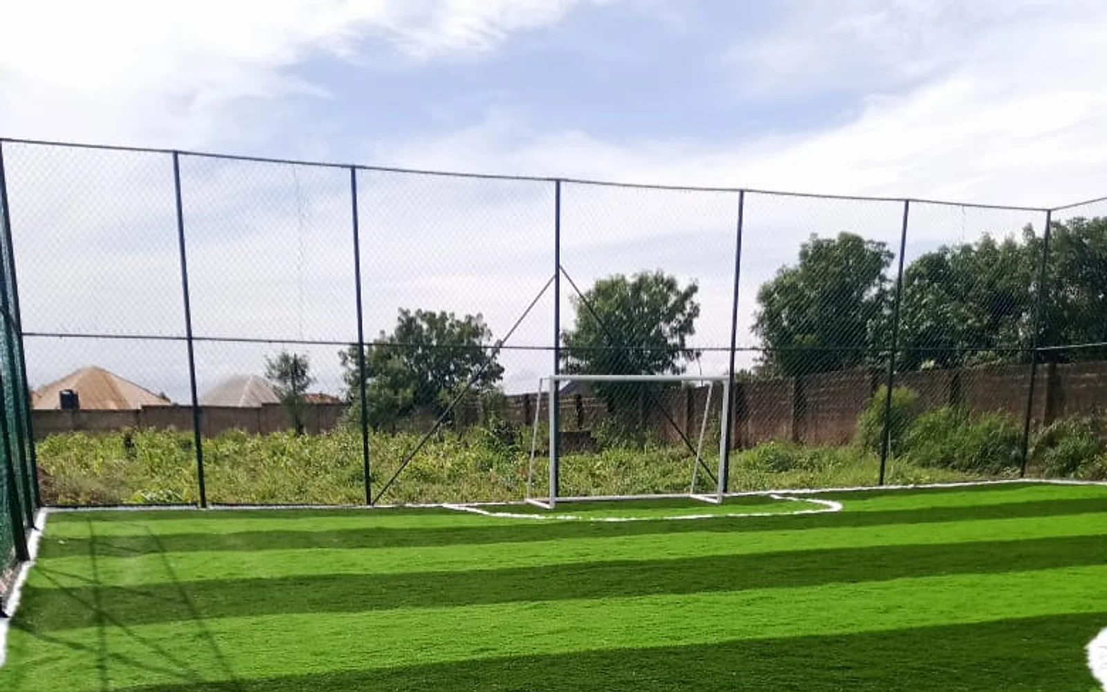 Wide view of the goal, turf and perimeter enclosure at the Nigeria football pitch