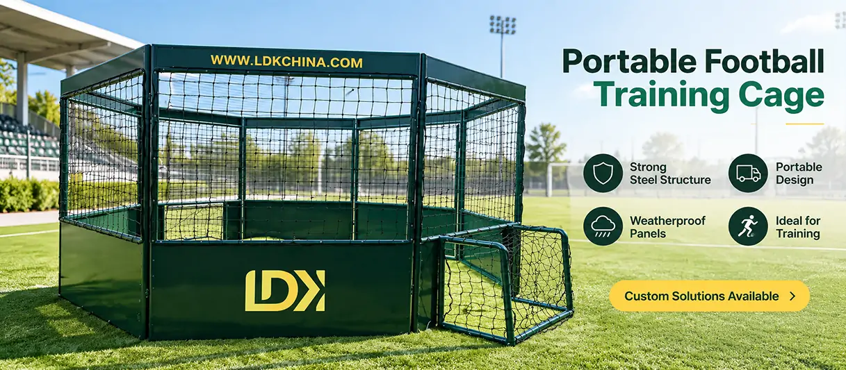 Dark green enclosed mini football cage with netting and a small goal displayed outside a sports equipment facility.